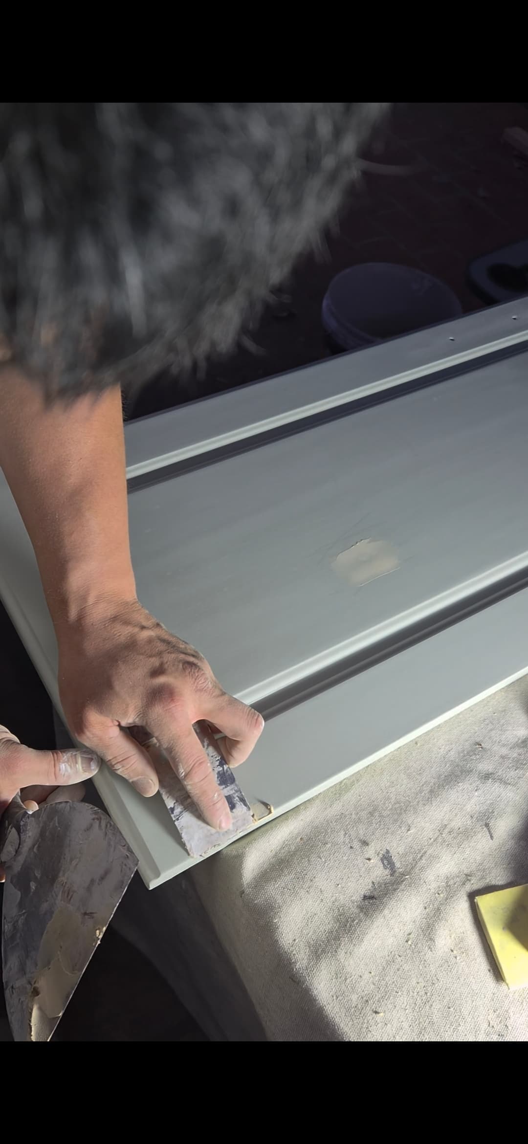 Company-provided photograph of a worker repairing the surface of a cabinet door.